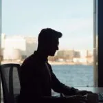 Profissional usando notebook com painéis de dados e interface digital, para o artigo Como usar inteligência artificial no ...